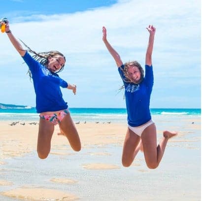 two girls jumping on the beach