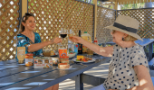 two women enjoying food and clinking wine glasses in the BBQ area at Rainbow Beach Holiday Village